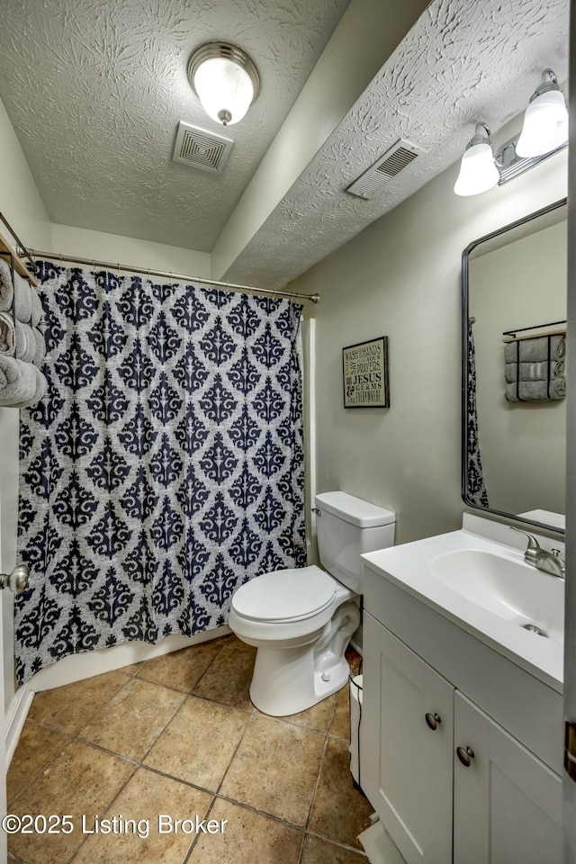 bathroom with vanity, a textured ceiling, tile patterned floors, toilet, and walk in shower