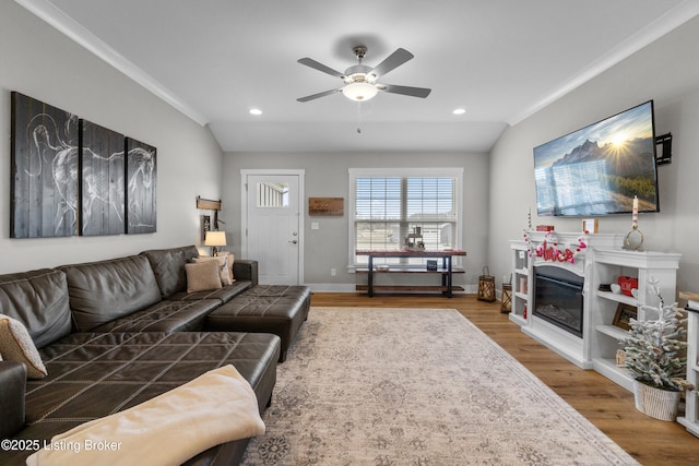 living room featuring hardwood / wood-style flooring, ceiling fan, lofted ceiling, and ornamental molding