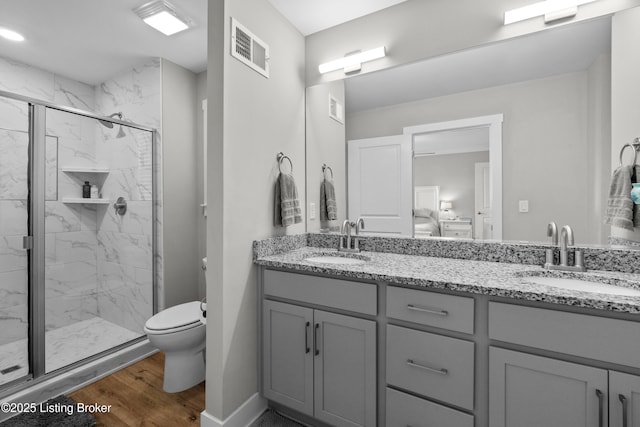 bathroom with hardwood / wood-style flooring, vanity, a shower with door, and toilet