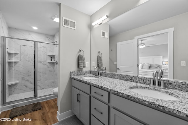 bathroom with a shower with door, ceiling fan, hardwood / wood-style floors, vanity, and toilet