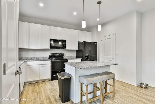 kitchen with decorative light fixtures, white cabinetry, a center island, light hardwood / wood-style floors, and black appliances