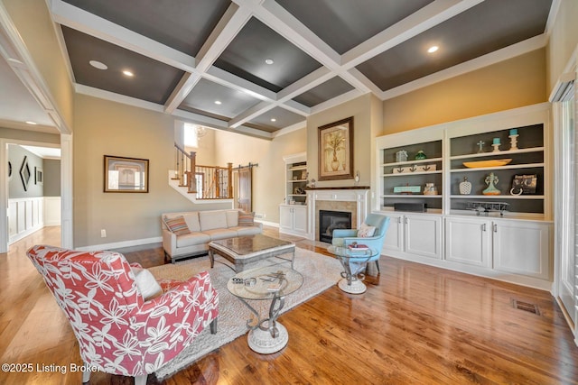 living room featuring visible vents, beamed ceiling, coffered ceiling, stairway, and a fireplace