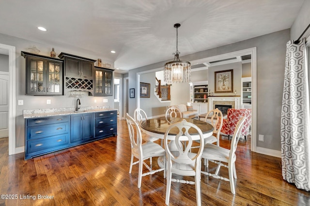 dining area with dark wood-style floors, wet bar, baseboards, and a glass covered fireplace