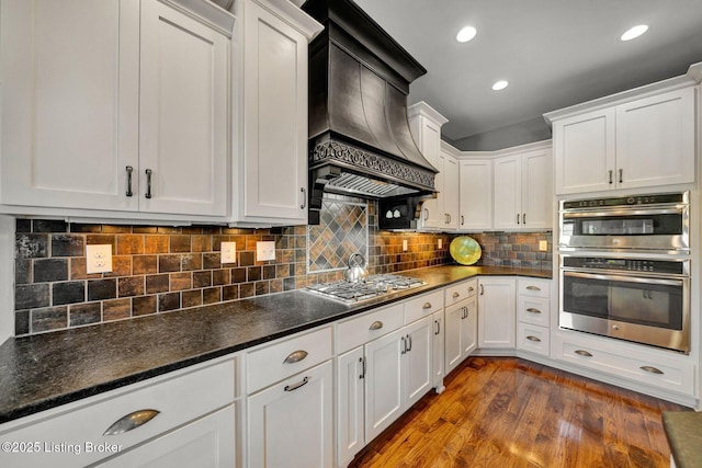 kitchen with custom exhaust hood, white cabinets, dark wood-style floors, and stainless steel appliances