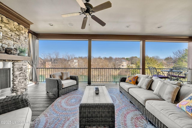 sunroom / solarium featuring a fireplace, a healthy amount of sunlight, and a ceiling fan