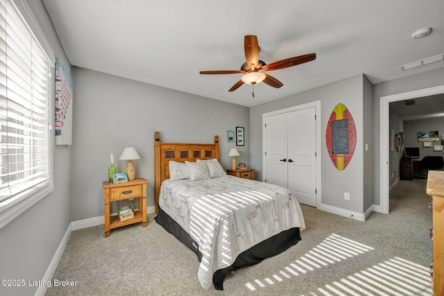 carpeted bedroom with a closet, baseboards, and a ceiling fan