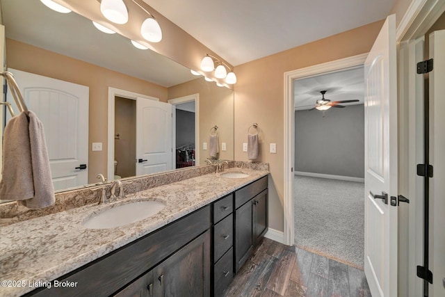 full bathroom with double vanity, wood finished floors, baseboards, and a sink