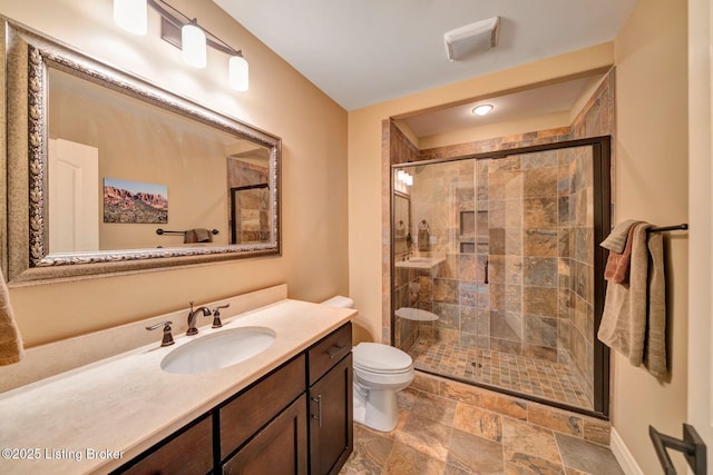 bathroom featuring visible vents, stone finish flooring, toilet, a stall shower, and vanity