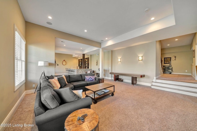 carpeted living area with recessed lighting, a tray ceiling, and baseboards