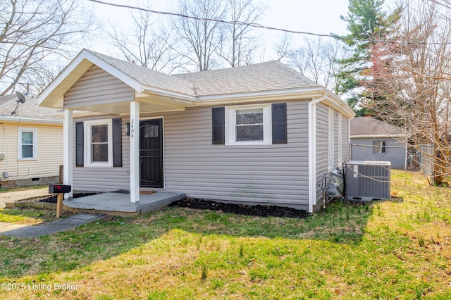 bungalow-style home featuring a front lawn, central AC unit, fence, and roof with shingles