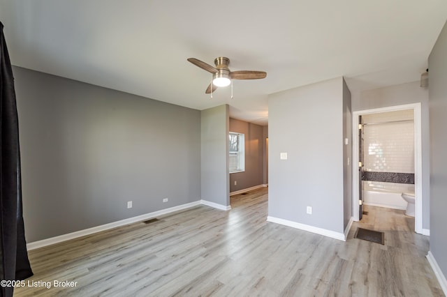 unfurnished bedroom with visible vents, baseboards, wood finished floors, and ensuite bathroom