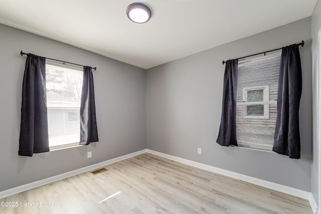 empty room featuring visible vents, baseboards, and wood finished floors