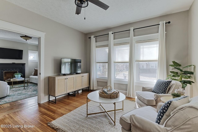 living room featuring hardwood / wood-style flooring, ceiling fan, and a textured ceiling