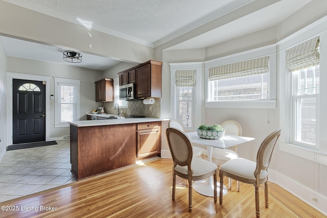 kitchen featuring sink, backsplash, kitchen peninsula, a textured ceiling, and light hardwood / wood-style flooring