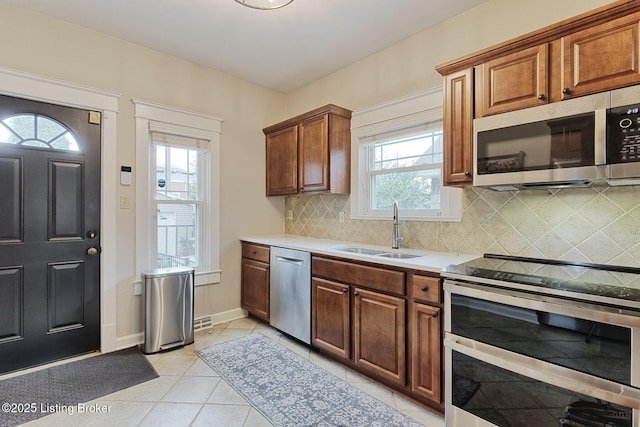 kitchen featuring sink, backsplash, stainless steel appliances, and light tile patterned floors