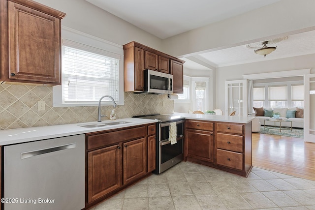 kitchen with tasteful backsplash, sink, kitchen peninsula, and appliances with stainless steel finishes