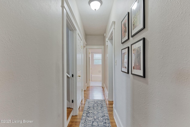 corridor with hardwood / wood-style floors and a textured ceiling