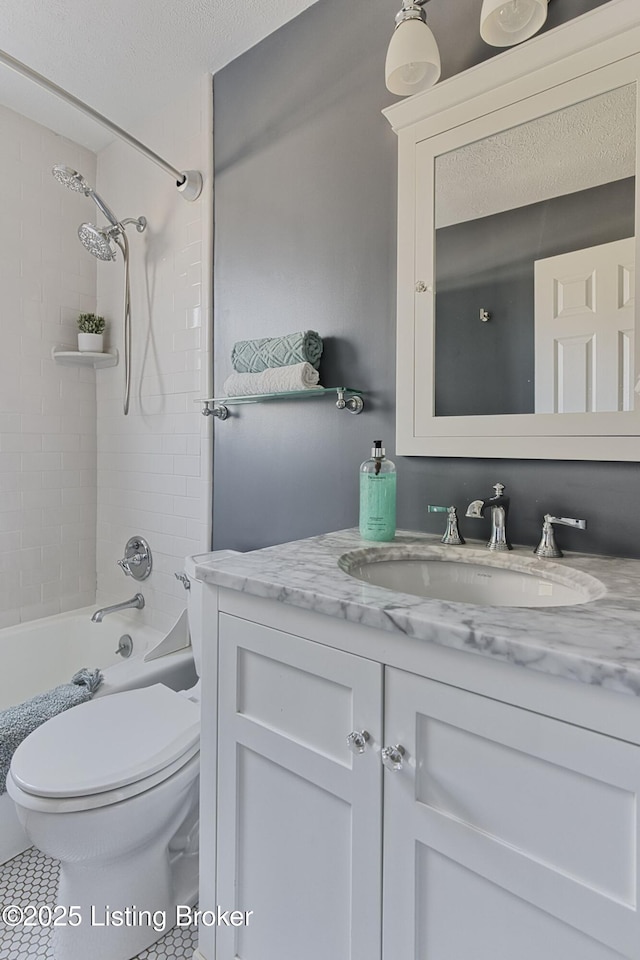 full bathroom with vanity, tiled shower / bath, a textured ceiling, and toilet