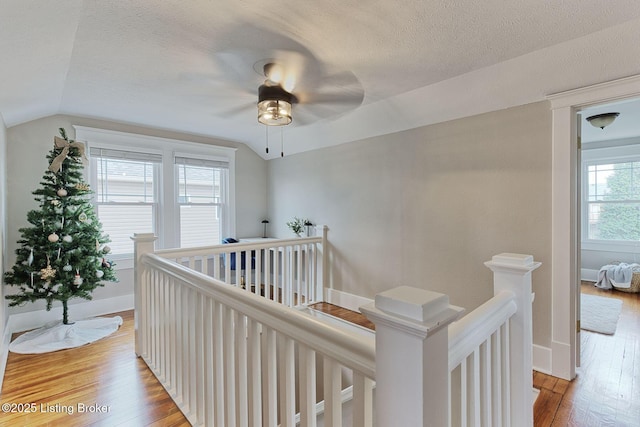 hall with lofted ceiling, light hardwood / wood-style floors, and a textured ceiling