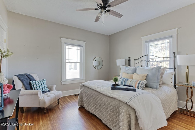 bedroom featuring multiple windows, hardwood / wood-style flooring, and ceiling fan