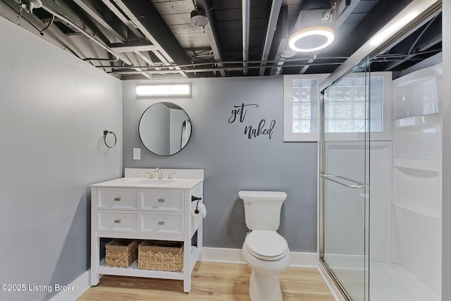 bathroom with hardwood / wood-style flooring, vanity, toilet, and a shower with door