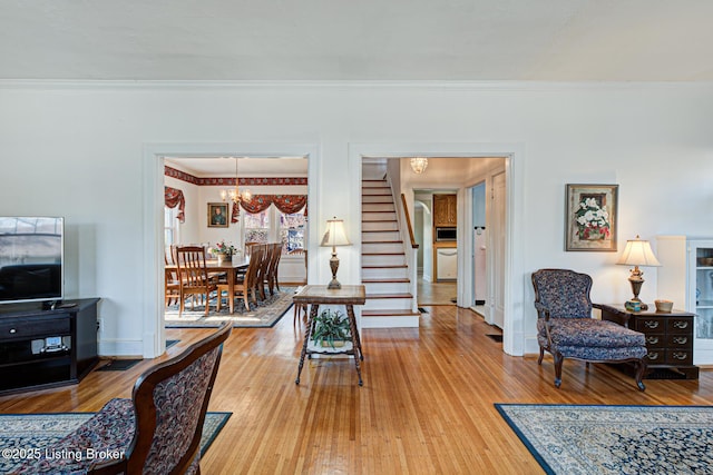 living room with hardwood / wood-style floors, ornamental molding, and a chandelier