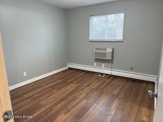 empty room featuring a baseboard radiator, dark hardwood / wood-style flooring, and a wall mounted AC