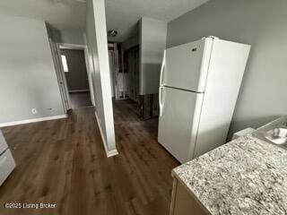 kitchen featuring light stone countertops, dark hardwood / wood-style floors, white cabinets, and white fridge