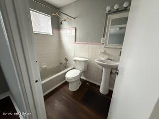 full bathroom featuring toilet, sink, wood-type flooring, tile walls, and tiled shower / bath combo