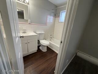 full bathroom featuring tiled shower / bath, tile walls, hardwood / wood-style flooring, vanity, and toilet