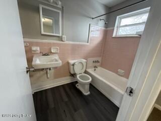 full bathroom with tiled shower / bath, hardwood / wood-style floors, sink, tile walls, and toilet