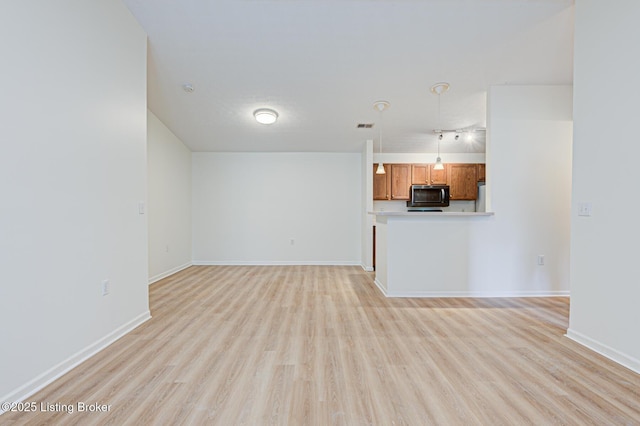 unfurnished living room featuring light wood-type flooring, visible vents, and baseboards