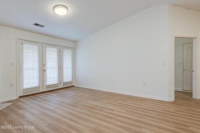 spare room with light wood-style flooring, visible vents, vaulted ceiling, and baseboards