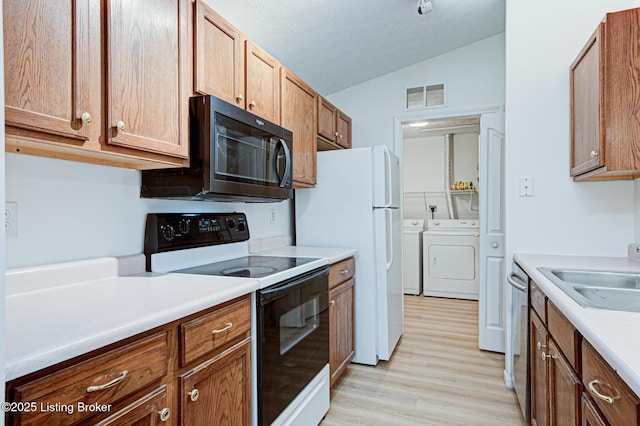 kitchen featuring visible vents, vaulted ceiling, a sink, range with electric cooktop, and independent washer and dryer