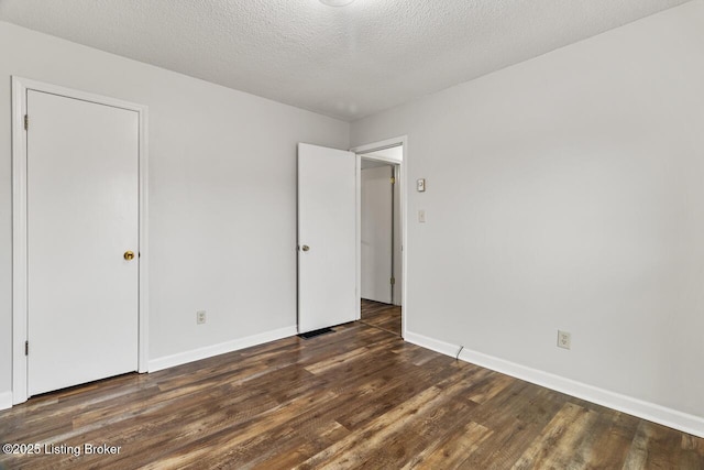 unfurnished bedroom featuring a textured ceiling and dark hardwood / wood-style flooring