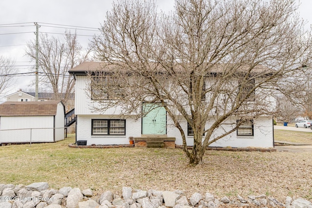 view of front of home featuring a front lawn and a storage unit