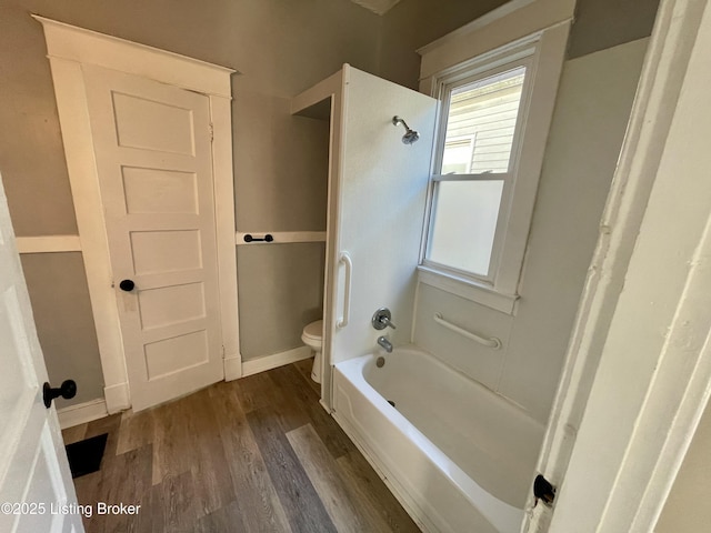 bathroom with wood-type flooring, toilet, and washtub / shower combination