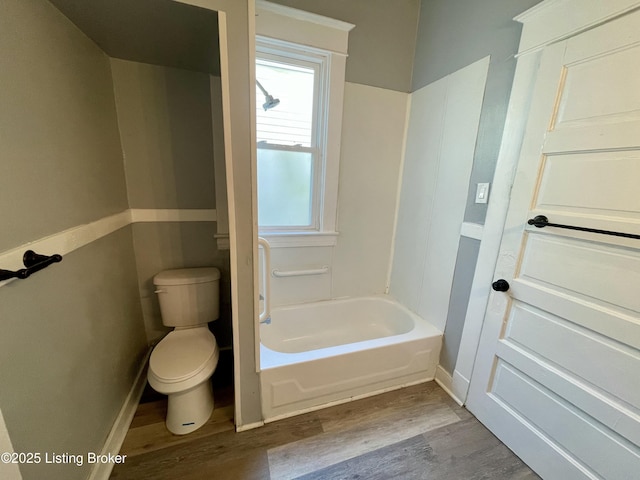 bathroom featuring hardwood / wood-style flooring, shower / washtub combination, and toilet