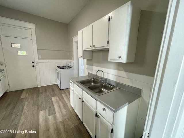 kitchen with sink, white gas range oven, white cabinets, and light wood-type flooring