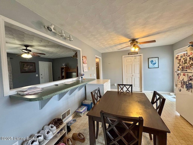 dining area with ceiling fan and a textured ceiling