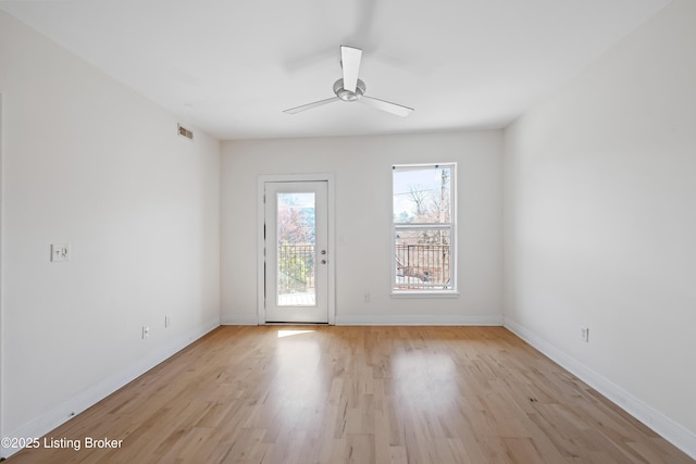 spare room featuring light wood-type flooring, visible vents, baseboards, and a ceiling fan