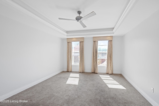 carpeted empty room featuring a tray ceiling, baseboards, and ceiling fan