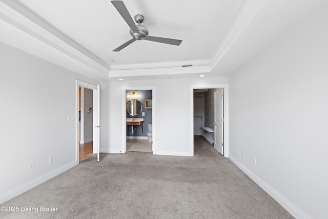 unfurnished bedroom featuring a spacious closet, visible vents, baseboards, carpet, and a raised ceiling