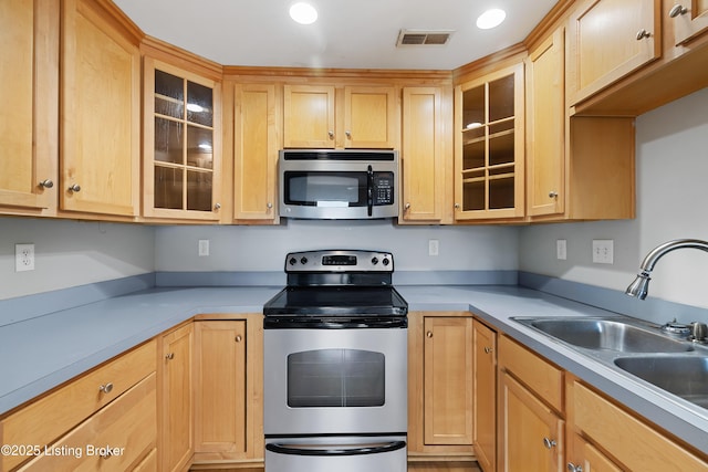 kitchen featuring light brown cabinetry, visible vents, appliances with stainless steel finishes, and a sink