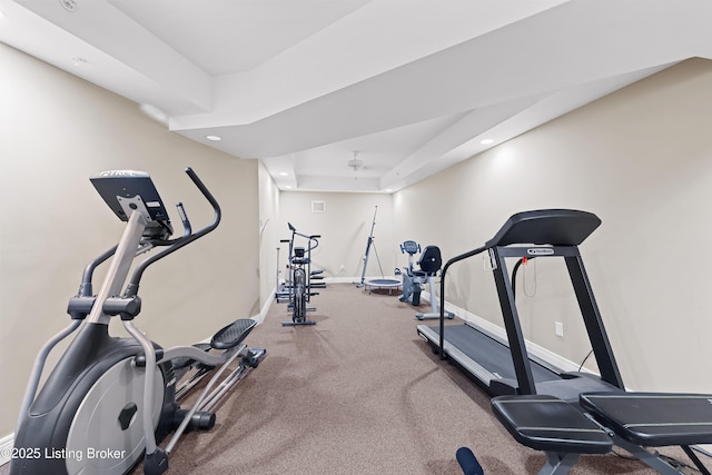 workout room featuring recessed lighting, a raised ceiling, and baseboards