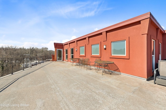 rear view of house featuring a patio, fence, and stucco siding