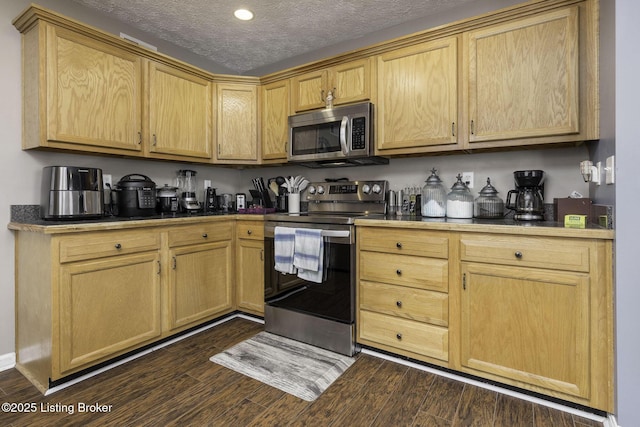 kitchen featuring dark wood finished floors, stainless steel appliances, dark countertops, light brown cabinetry, and a textured ceiling