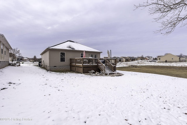 snow covered back of property with crawl space and a deck