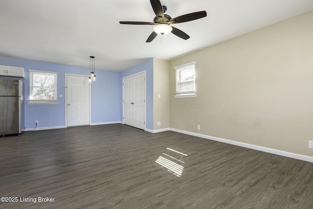 unfurnished living room with ceiling fan, dark wood-type flooring, and a healthy amount of sunlight