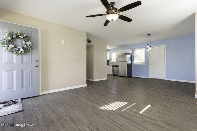 unfurnished living room featuring dark wood-type flooring and ceiling fan